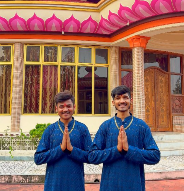 Soni Brothers in blue kurtas with folded hands in front of a temple